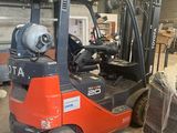 un chariot élévateur rouge garé dans un entrepôt, à côté d'une palette