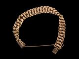 un bracelet en chaîne dorée muni d'un fermoir, sur fond noir
