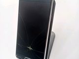 a broken samsung phone sitting on top of a stand