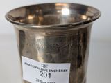 an old silver cup with a sticker on it sitting on a table