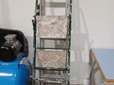 une échelle appuyée contre un mur, à côté d'un compresseur d'air bleu