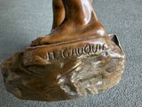 statue en bronze représentant une femme assise sur un rocher, les pieds posés sur le sol