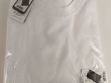 Le t-shirt blanc est emballé dans du plastique et porte une étiquette.