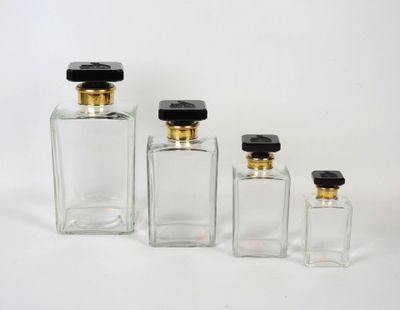 trois bouteilles en verre transparent avec des couvercles noirs et des bouchons dorés
