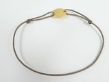 a close up of a bracelet with a gold disc on a white background