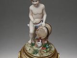 an antique figurine of a boy with a basket of fruit