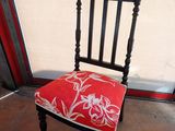 a chair with a red cushion on it in front of a glass door