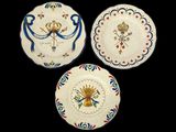 trois assiettes ornées de motifs, posées sur une surface noire