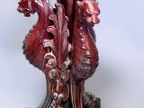 un vase rouge orné d'un dragon, posé sur un socle
