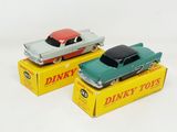 two toy cars sitting on top of boxes on a white surface