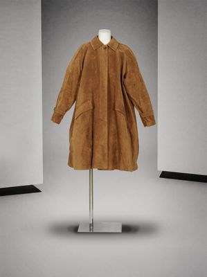une photo d'un manteau marron posé sur un portant dans une pièce