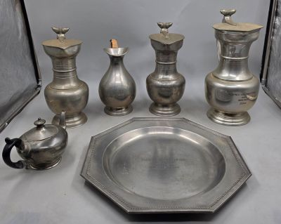 de nombreux vases en argent et un plateau en argent posés sur une table