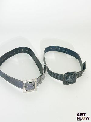 une paire de ceintures en cuir noir avec des boucles argentées, sur fond blanc