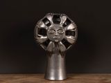 an image of a silver sculpture of a face on a wooden table
