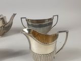 two silver plated teapots and a saucer on a white surface
