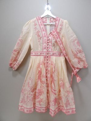 a white and pink dress hanging on a hanger on a wall