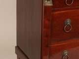 a small wooden chest of drawers with a marble top