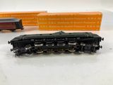 a black train on a white table next to a box of orange boxes