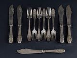 six forks and a knife on a black table
