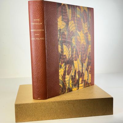an old book sitting on top of a wooden stand on a white surface