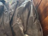 leather jacket laying on a bed in a bedroom next to a dresser