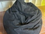 a black bean bag sitting on the floor in front of a bench