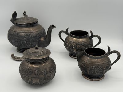 three silver teapots and two cups on a white surface