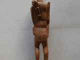 statue en bois représentant un homme portant un chapeau et un sac sur le dos