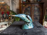 a statue of a bird sitting on top of a wooden table