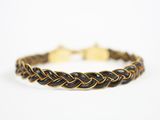 un bracelet tressé noir et doré sur fond blanc
