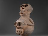 une vieille figurine en argile représentant un homme tenant un crâne