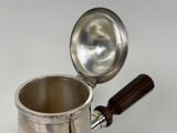 a silver coffee pot with a wooden handle on a white surface