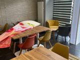 une table et des chaises dans une pièce, avec une fenêtre en arrière-plan