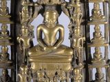 brass statue of a person sitting on a throne with a heart in the center