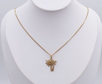 un collier en or avec un pendentif en forme de palmier sur un mannequin