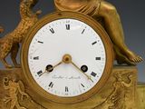 a gold clock with a statue of a woman and a dog