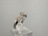 une photo d'une bague en diamant posée sur un socle transparent