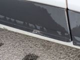 a white car with black paint on the side of the road