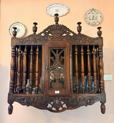 a clock on the wall next to a shelf with plates on it