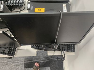 une personne debout devant un écran d'ordinateur et un clavier