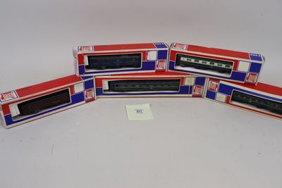 quatre trains miniatures dans leurs boîtes, empilés les uns sur les autres sur une surface blanche