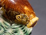 a brown and green fish figurine on a black surface