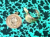 une pièce d'or et une bague en argent sur un fond vert