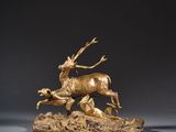 une sculpture en bronze représentant un cerf et une biche sur un rocher