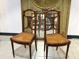 une paire de chaises anciennes avec des dossiers en rotin dans une pièce où se trouve un miroir