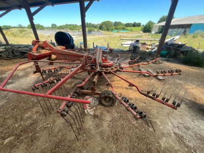une grosse machine rouge posée au milieu d'un champ de terre battue