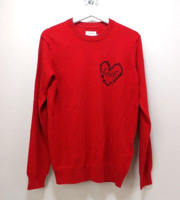 un pull rouge orné d'un cœur, suspendu à un cintre