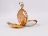 an antique gold pocket watch with a chain on a white background