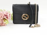 a black gucci bag with a chain and flowers in the background
