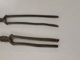three old metal tongs sitting on top of a white table